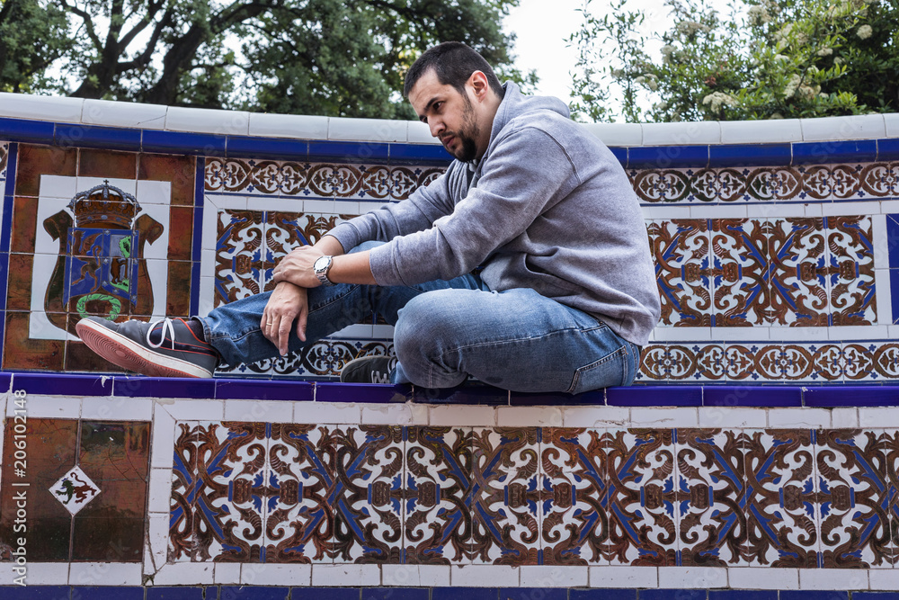 Fototapeta premium hombre sentado en banco de azulejos arabes