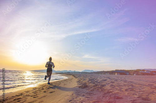 Healthy young fitness woman runner running on sunrise seaside trail