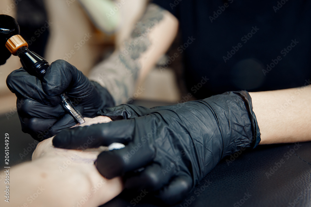 Fototapeta premium Tattoo process machine close-up. master prepares for procedure of drawing