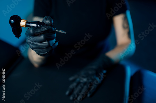 Woman master arm holding tattoo machine, preparing for drawing picture