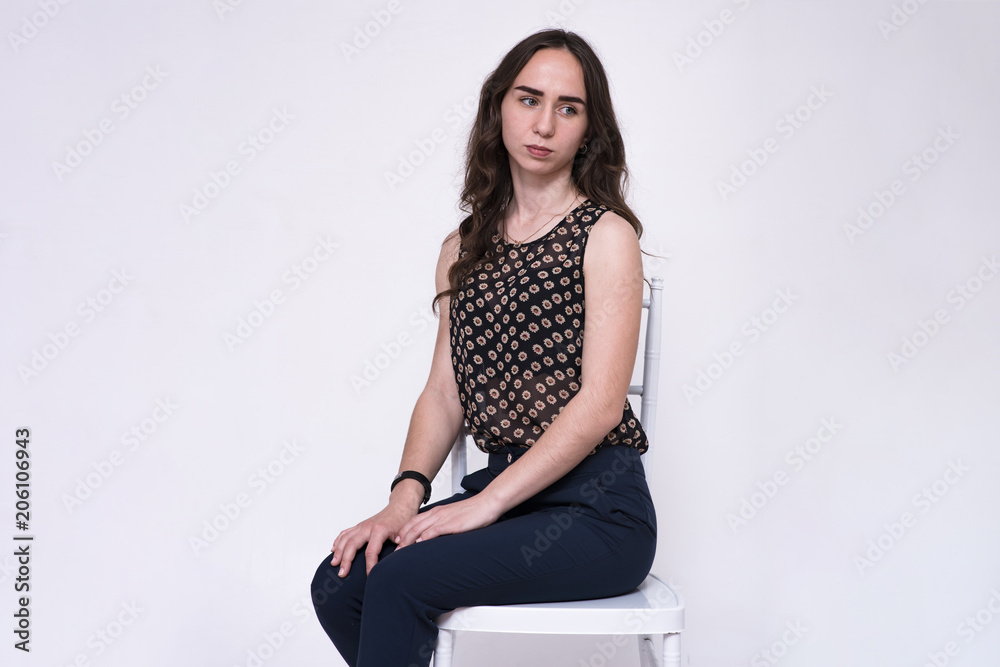 portrait of a young beautiful brunette girl on a white background sitting on a chair. portrait of a young beautiful brunette girl on a white background sitting on a chair.