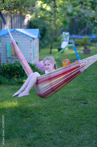 Girl playing with a hammock on the lawn on the playground