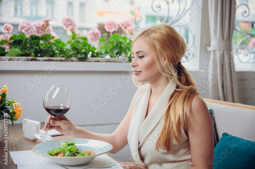 Young blonde woman drinking red wine in an outdoor restaurant