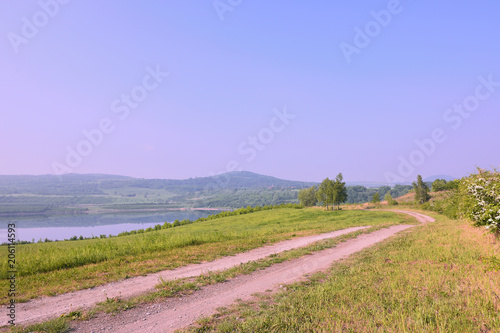 Czech landscape with meadow path leading to new lake named Milada and mountains in spring morning