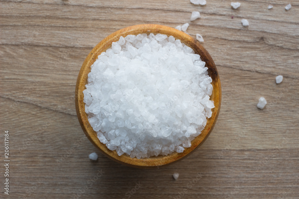 Top view of Salt or sea salt in a wooden bowl on a wooden table background. Top view of Salt or sea salt in a wooden bowl on a wooden table background.