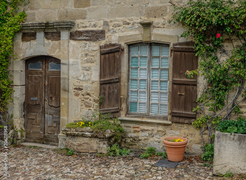 Najac, Midi Pyrenees, France - September 16, 2017: Old stone facade with wooden door and window surrounded by vines