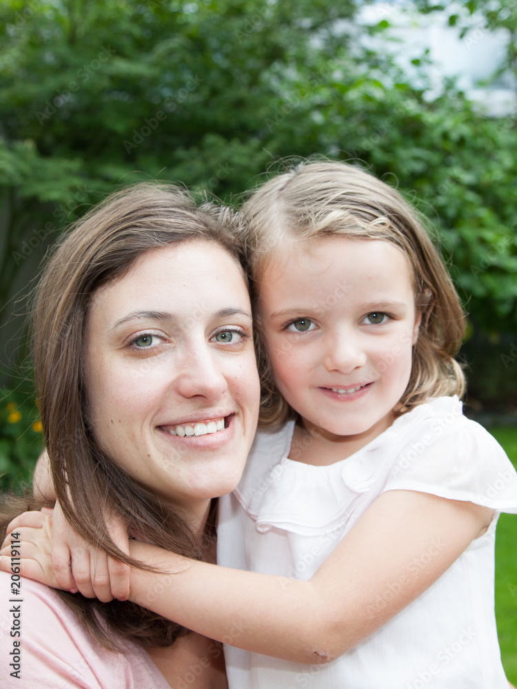 Mother and daughter sitting together on green grass having fun Mother and daughter sitting together on green grass having fun