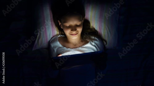 digital modern device addiction. gadget night sleeplessness. young caucasian girl browsing chatting playing serfing network with tablet bed. mobile phone apps. photo