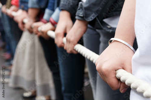 Various people pulling rope together, closeup of hands. Teamwork. Unity concept. Selective focus