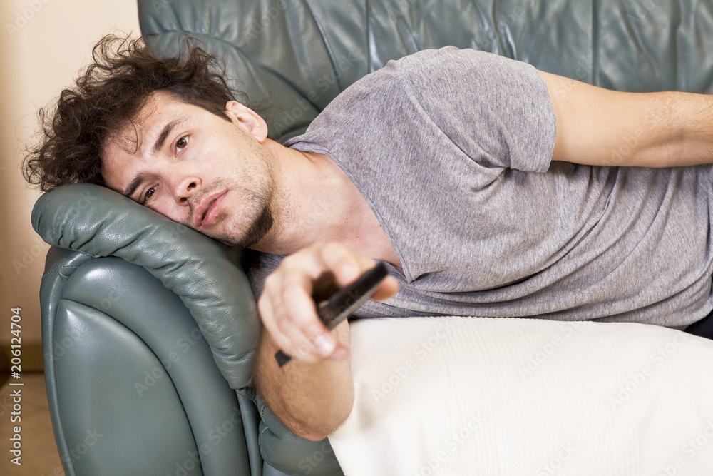 Lazy man with the remote on the couch - obrazy, fototapety, plakaty 