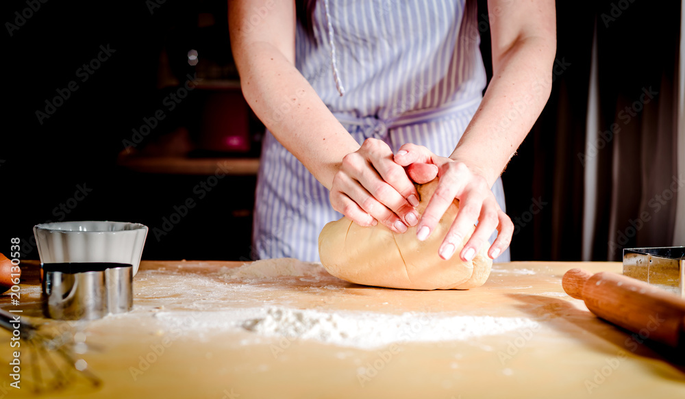 Female hands making dough on wooden table