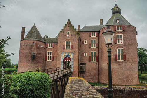 Medieval Ammersoyen Castle with its brick towers, wooden bridge and green garden on cloudy day. Near to the historic and vibrant city of s-Hertogenbosch. Southern Netherlands photo