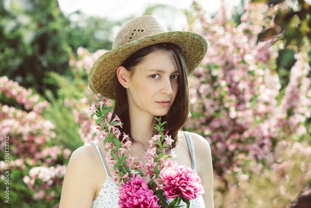 Portrait of young woman with bouquet of flowers in the garden