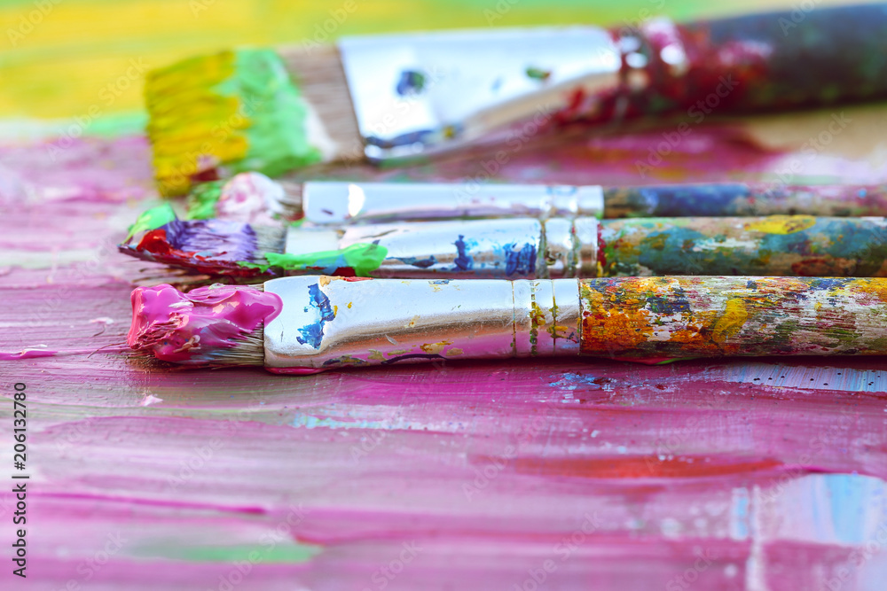 Closeup of paintbrushes on colourful background   