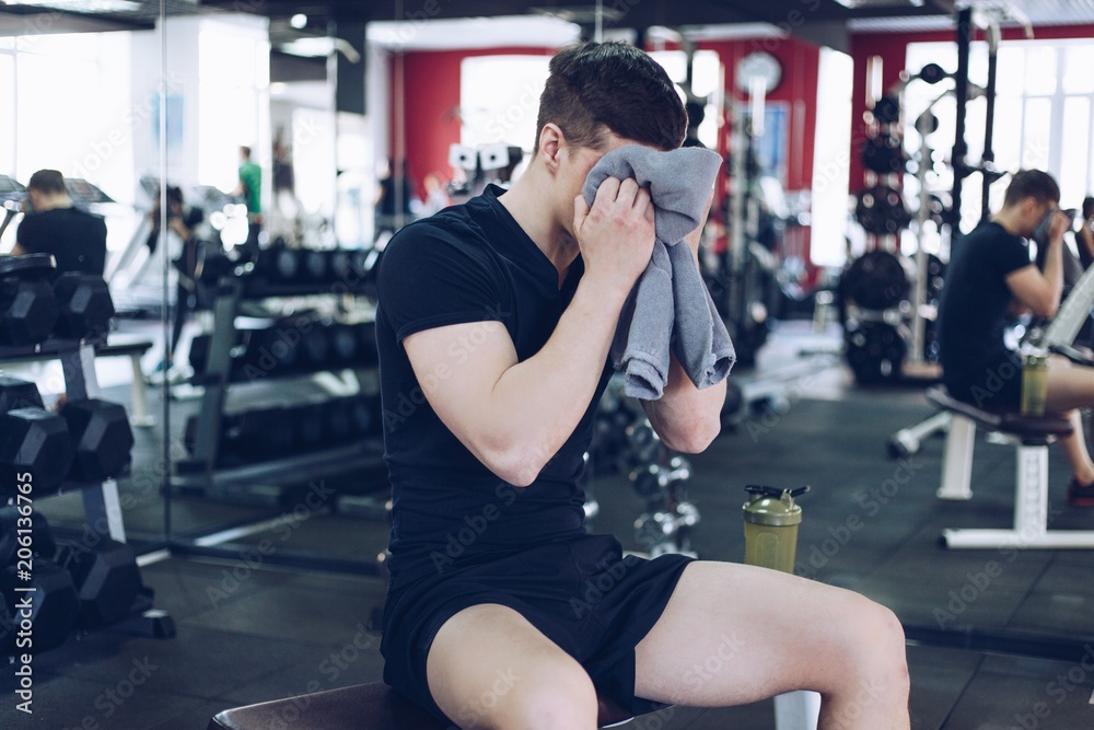 Muscular man wipes with a towel after exercise Muscular man wipes with a towel after exercise