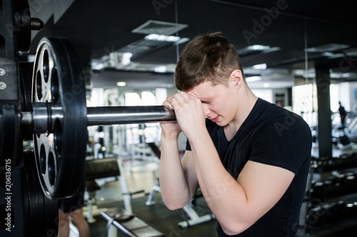 Bodybuilder man in black sportswear preparing for a heavy weight training session