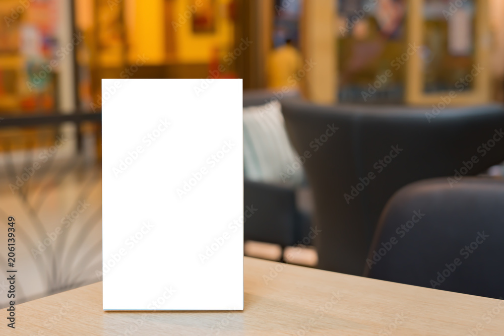 Mock up Label the blank menu frame in Bar restaurant ,Stand for booklets with white sheets paper acrylic tent card on wooden table cafeteria blurred background can inserting the text of the customer.