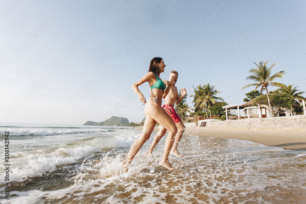 Fototapeta premium Cheerful couple running at the shore