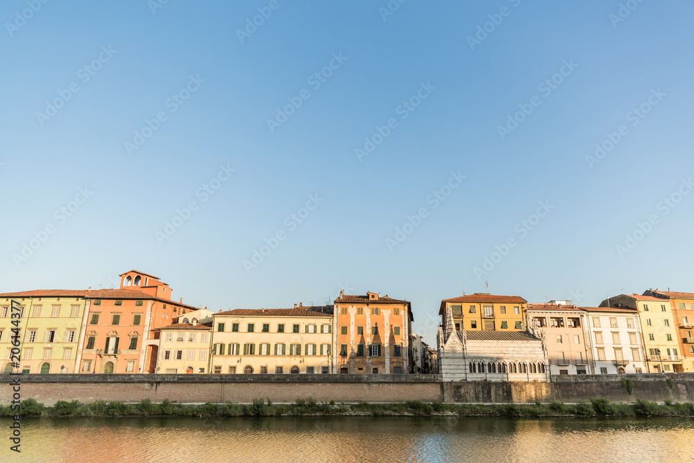 ancient buildings near river in old city with blue sky, Pisa, Italy