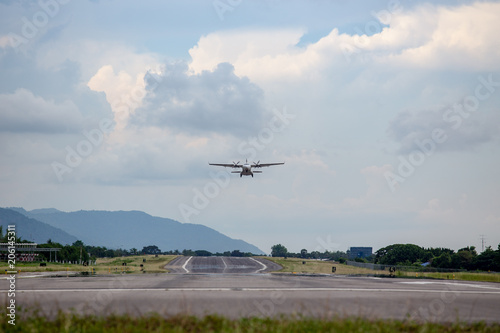 twin engines propeller aircraft take off from runway and climb with cloud and sky background