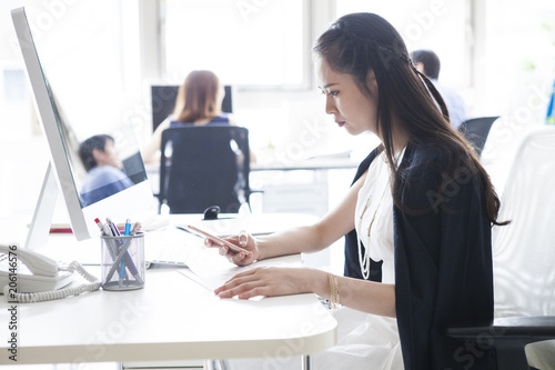 女性は仕事中にスマートフォンを見ている