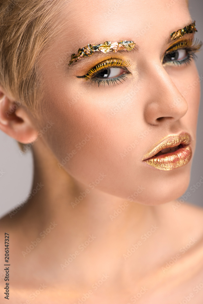 attractive caucasian woman with golden glitter on face looking at camera