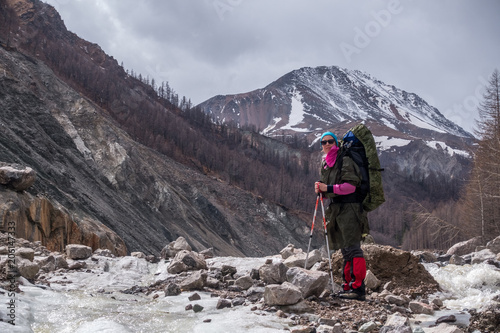 A tourist stands in the middle of a mountain river