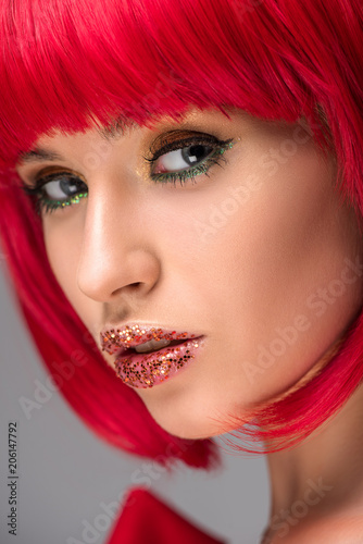 headshot of attractive woman with red hair and glitter on face looking at camera