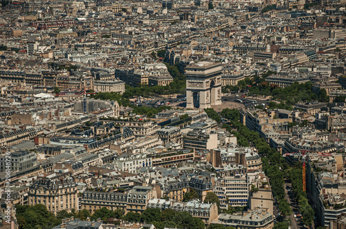 The Arc de Triomphe and buildings under blue sky, seen from the Eiffel Tower top in Paris. Known as the “City of Light”, is one of the most impressive world’s cultural center. Northern France.