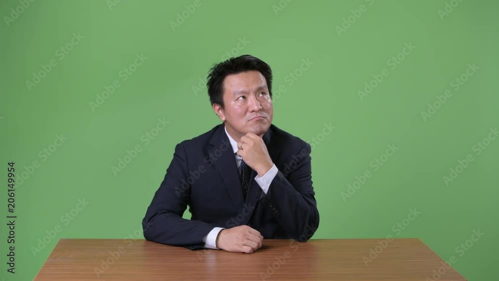 Mature Japanese businessman against green background Mature Japanese businessman against green background