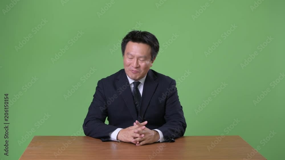 Mature Japanese businessman against green background Mature Japanese businessman against green background