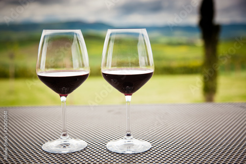 two glasses of red wine against beautiful landscape in Tuscany