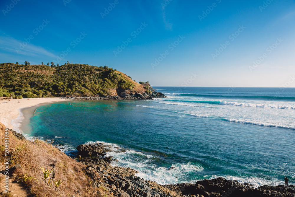 Tropical beach and waves for surfing in ocean with blue sky