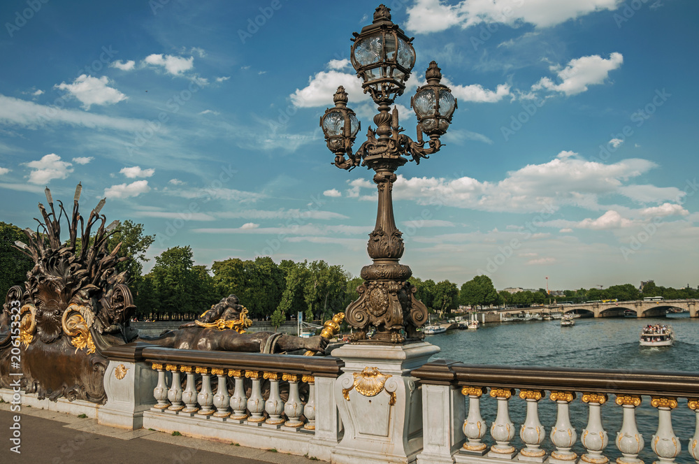 Fototapeta premium Touristic boat passing under the lavishly decorated Alexandre III bridge at the Seine river in Paris. Known as the “City of Light”, is one of the most awesome world’s cultural center. Northern France.