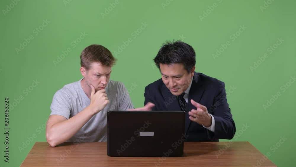 Mature Japanese businessman and young Scandinavian man worker together Mature Japanese businessman and young Scandinavian man worker together