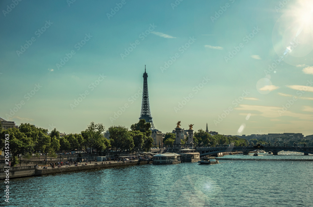Seine River bank with trees, bridge and Eiffel Tower at sunset in Paris. Known as the “City of Light”, is one of the most impressive world’s cultural center. Northern France. Retouched photo