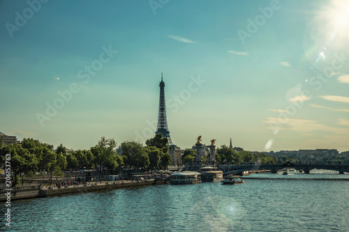 Seine River bank with trees, bridge and Eiffel Tower at sunset in Paris. Known as the “City of Light”, is one of the most impressive world’s cultural center. Northern France. Retouched photo