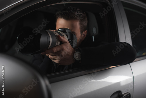 paparazzi doing surveillance by camera with lens from his car