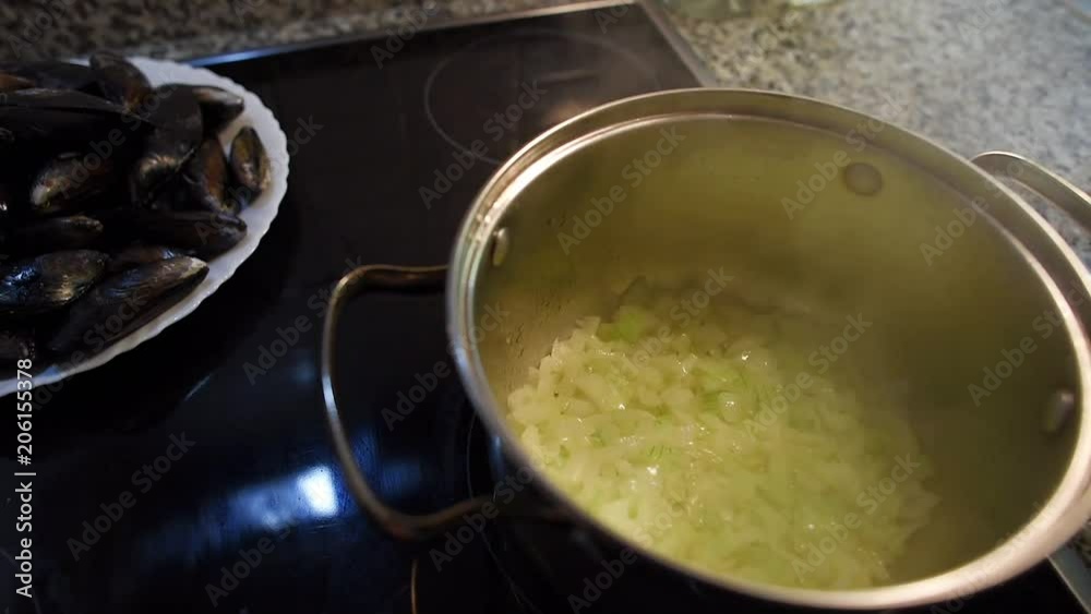 Close-up of an onion being fried in a pan. Steam above the pot. Preparation of white sauce for mussels. Close-up of an onion being fried in a pan. Steam above the pot. Preparation of white sauce for mussels.