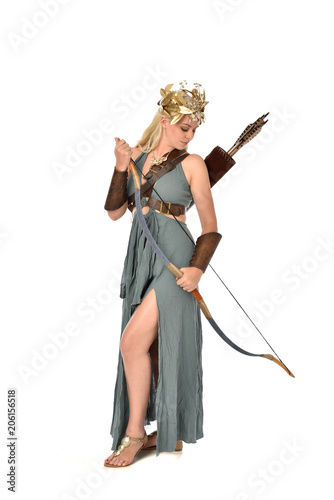full length portrait of pretty blonde lady wearing fantasy toga gown,  and holding a bow and arrow. standing pose on white background. © faestock