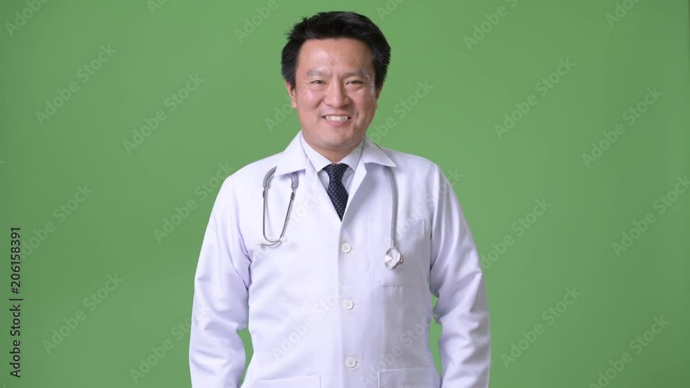 Mature Japanese man doctor against green background Mature Japanese man doctor against green background