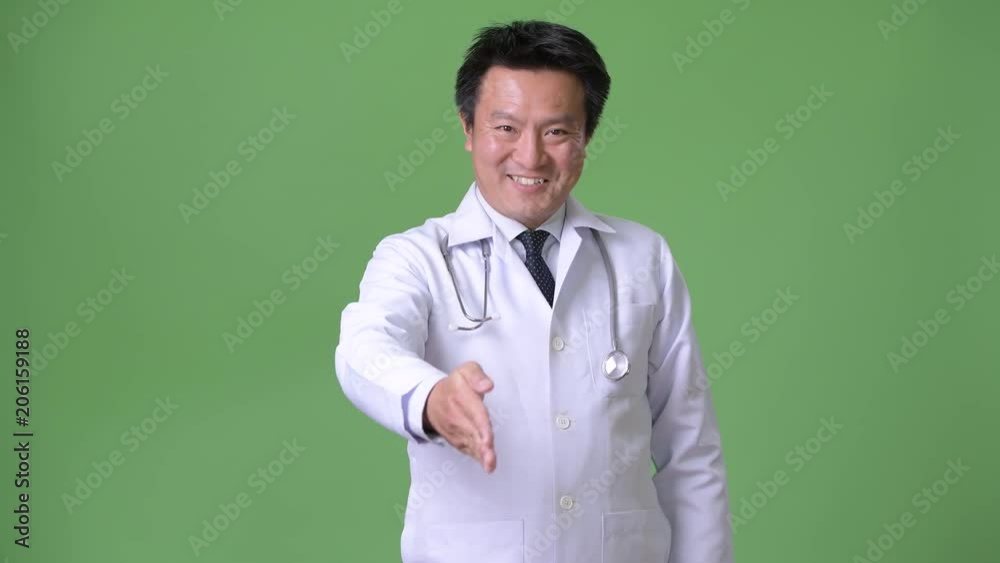 Mature Japanese man doctor against green background Mature Japanese man doctor against green background