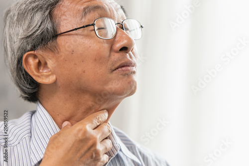 Asian elder old man Sore throat irritation and have a phlegm hand touching neck. photo