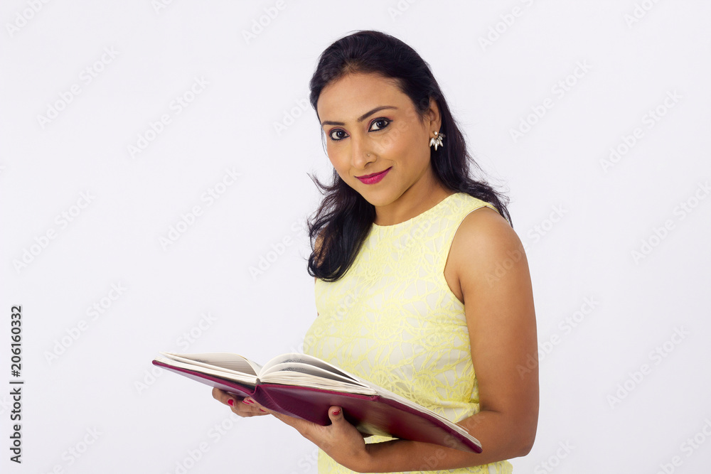 Smiling woman in yellow top holding a book. Side pose Smiling woman in yellow top holding a book. Side pose