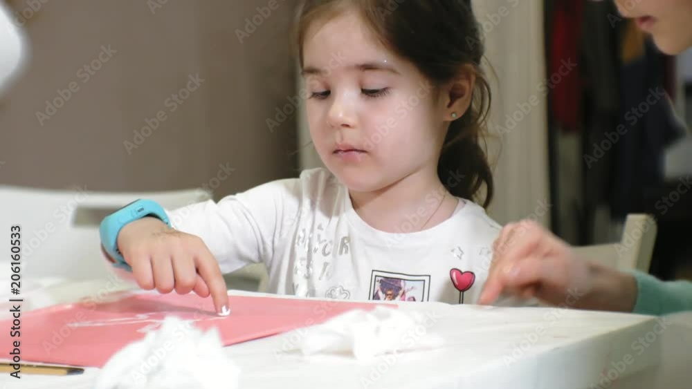 Children boys and girls sitting together around the table in classroom and drawing. With them is their young and beautiful teacher.