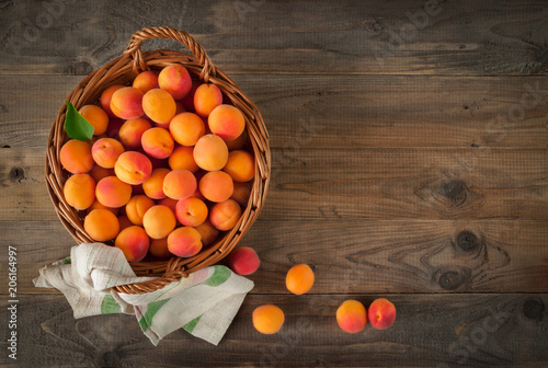 basket with ripe apricot on natural background wooden table. Top view. photo