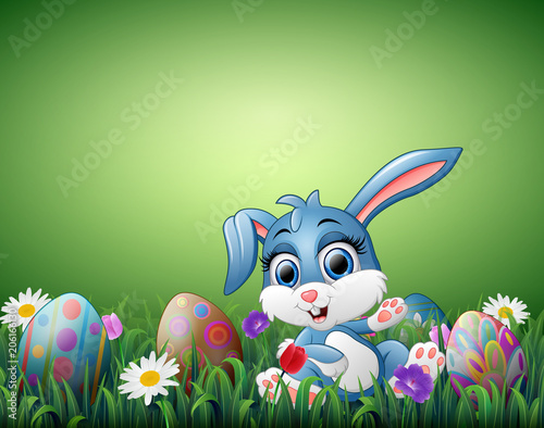 Cute little rabbit cartoon with decorated Easter eggs in a field