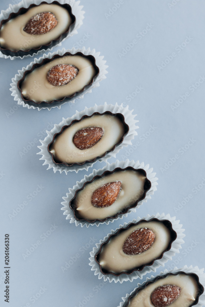Row of delicious praline sweets with almonds on blue background Row of delicious praline sweets with almonds on blue background