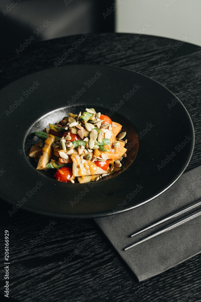 Fresh healthy dinner with seeds and vegetables on black plate Fresh healthy dinner with seeds and vegetables on black plate
