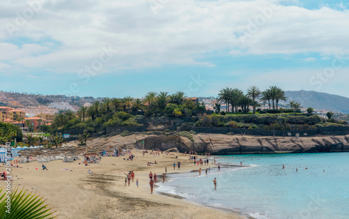 People enjoying the sun at El Duque beach with warm turquoise water and gold sand in Costa Adeje, Tenerife, Canary islands, Spain